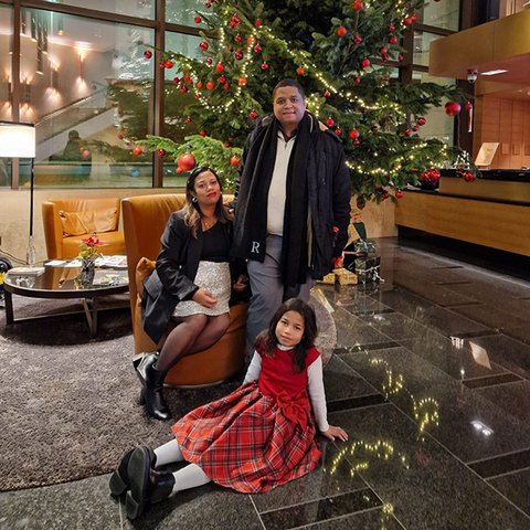 Laëtitia und ihre Eltern vor einem geschmückten Weihnachtsbaum