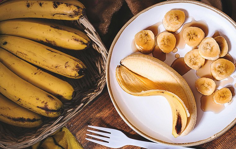 Korb mit Bananen und Teller mit zerschnittener Banane und Gabel