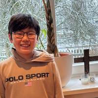 Manuel vor Fenster mit Kreuz und Kerzen mit verschneitem Garten im Hintergrund