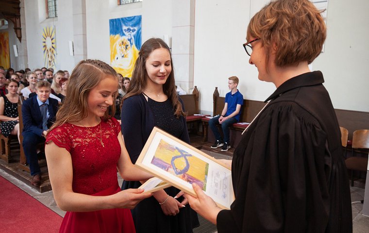 Pfarrerin mit zwei Konfirmandinnen in Kirche