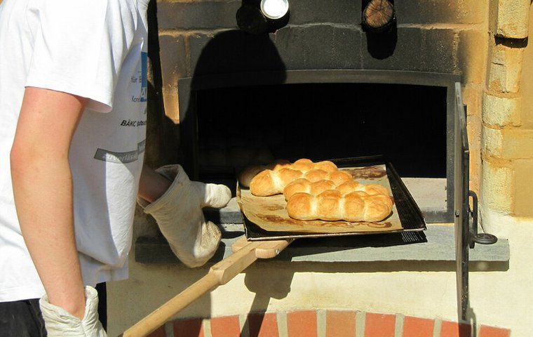 Bäcker schiebt Brot in Holzofen.