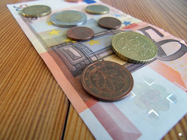 Verschiedene Cent- und Euro-Münzen auf 50-Euro-Schein