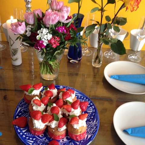 Gedeckter Tisch mit Blumen und Erdbeertörtchen