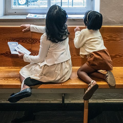 Laëtitia und kleineres Kind hocke auf Bank und schauen aus dem Fenster.