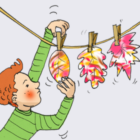 Kind hängt bunte Blätter mit Wäscheklammern zum Trocknen an Leine.