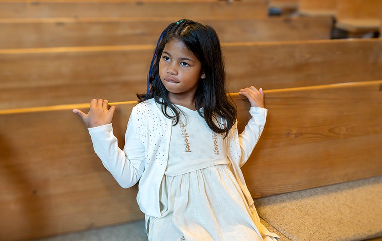 Laëtitia sitzt auf Kirchenbank der Friedenskirche Dachau.