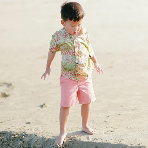 Kind in Sommerkleidung barfuß am Strand