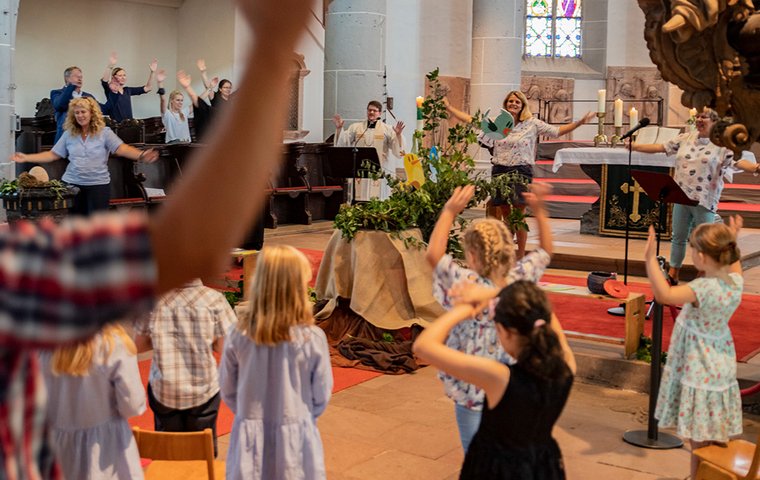Singende Kinder und Erwachsene in Kindergottesdienst in einer Kirche