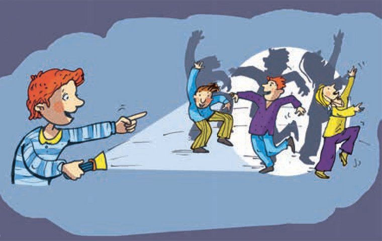 Rothaariger Junge beleuchtet tanzende Kinder mit Taschenlampe.