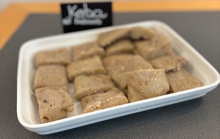 Platte mit eckigen Koba-Stücken und Schild "Koba mit Erdnüssen"