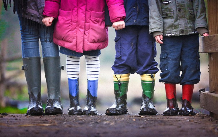 Vier paar Kinderbeine in Gummistiefeln