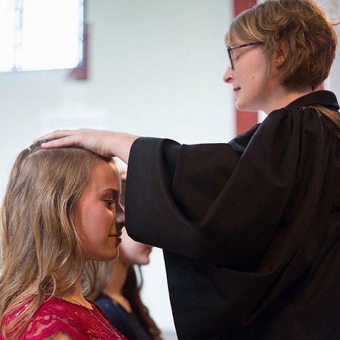 Pfarrerin segnet zwei Konfirmandinnen