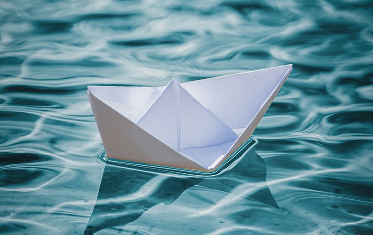 Weißes Papierschiff in türkisem Wasser