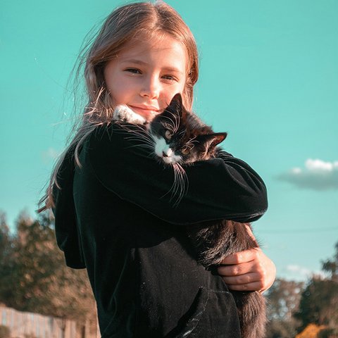 Mädchen mit schwarzer Katze auf dem Arm